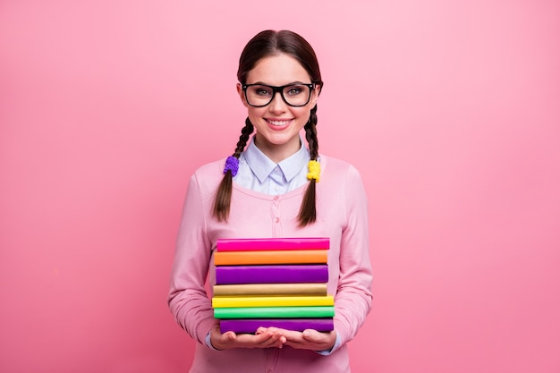 Portrait of her she nice attractive pretty lovely cute content cheerful intelligent girl geek holding in hands pile stack book isolated over pink pastel color background