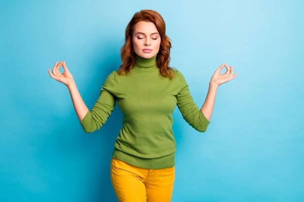 Portrait of her she nice attractive serene calm focused wavy-haired girl showing om gesture meditating isolated over bright vivid shine vibrant blue turquoise teal color wall