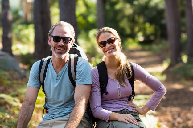 Portrait of hiker couple sitting on rock in forest