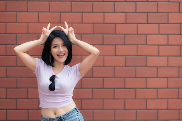 Portrait of hipster girl on brick wall backgroundBeautiful asian woman pose for take a photo