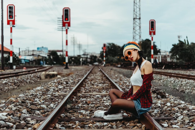 사진을 찍기 위해 포즈를 취하는 철도 빈티지 스타일타이 여성에 앉아 있는 힙스터 소녀의 초상화