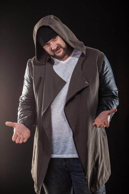 Photo portrait of hipster man gesturing while standing against black background