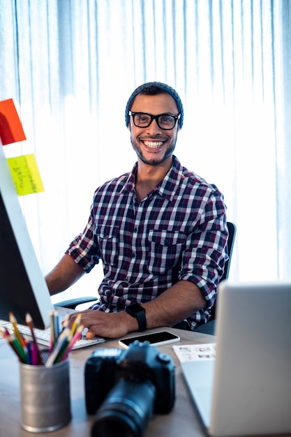 Portrait of hipster man photographer smiling while sitting at desk
