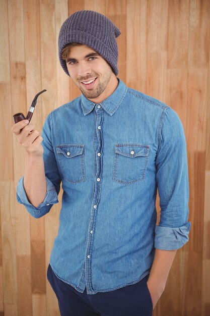 Portrait of hipster smiling while holding smoking pipe