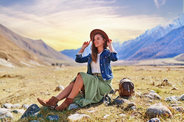 Portrait of a hipster young cute attractive smiling girl traveler travelling in a mountain valley