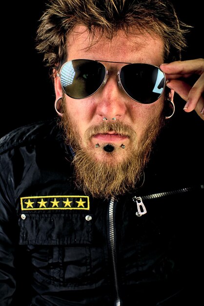 Photo portrait of hipster young man wearing sunglasses against black background