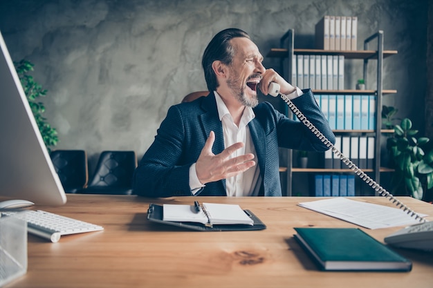 Portrait of his he depressed crazy desperate jobless guy qualified expert talking yelling on phone scandal fail at modern loft industrial style interior workplace workstation