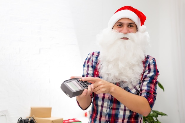 Portrait of his he nice attractive Santa holding in hand bank card digital terminal system commerce trade