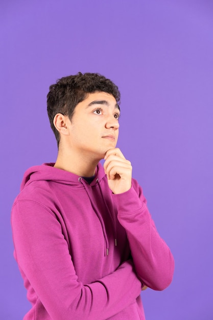 Portrait of hispanic boy thinking isolated on purple