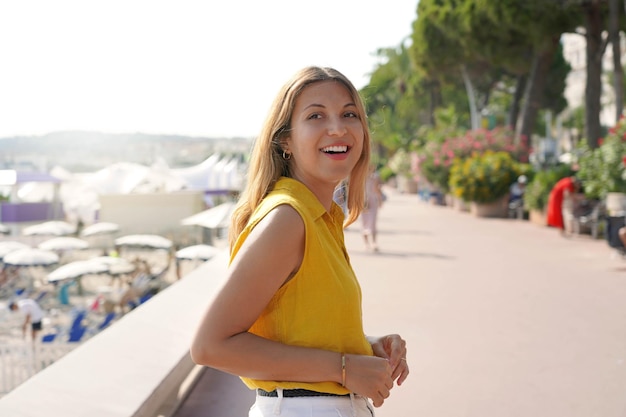 フランスのカンヌ遊歩道を歩く黄色いシャツを着たヒスパニック系の笑う女性のポートレート