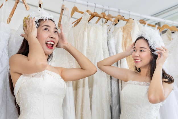 Portrait of homosexual couple in bride dress choosing dress in a shop.