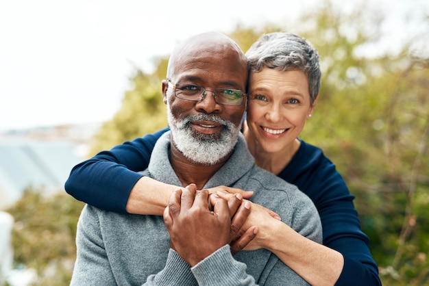 Portrait hug and senior couple with love interracial and marriage with happiness bonding and romance Face partners outside or mature woman with elderly black man embrace and romantic with smile
