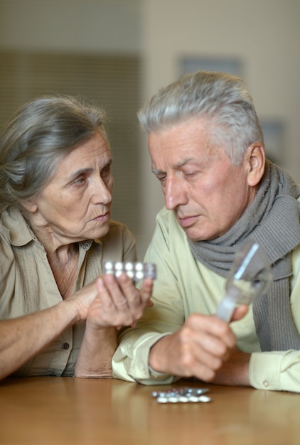 Portrait of ill senior couple with pills