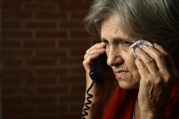 Portrait of ill senior woman calling doctor