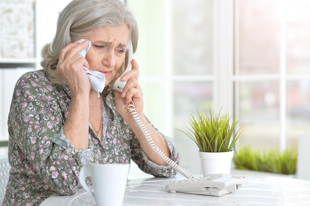 Portrait of ill senior woman calling doctor