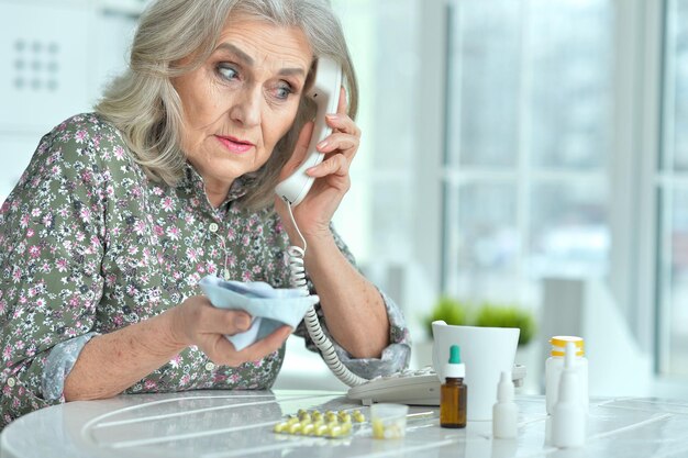 Portrait of ill senior woman calling doctor