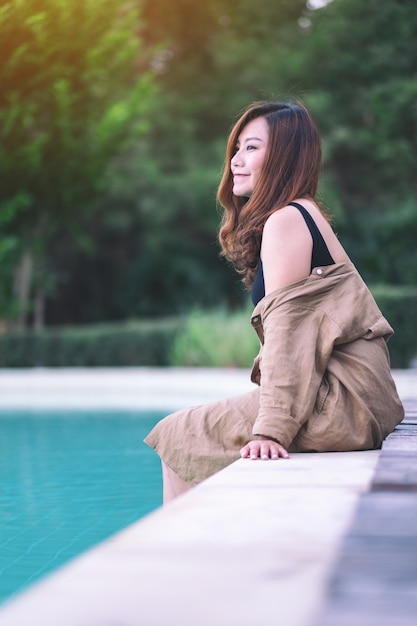 Portrait image of a beautiful asian woman enjoyed sitting by the swimming pool