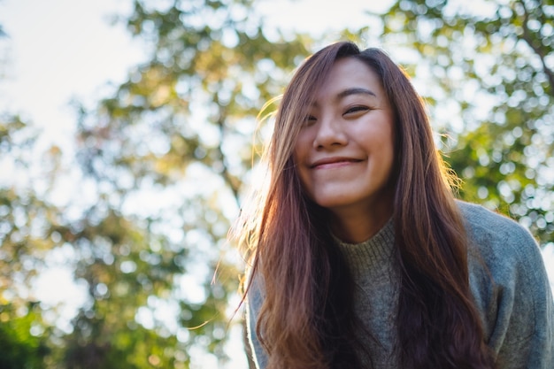 Immagine del ritratto di una bella donna asiatica in piedi tra la natura nel parco