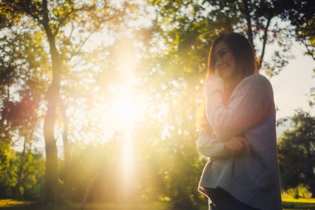 Portrait image of a beautiful asian woman standing among nature in the park before sunset