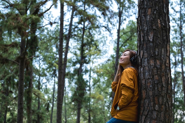 Portrait image of a beautiful young asian woman enjoy listening to music with headphone in the park