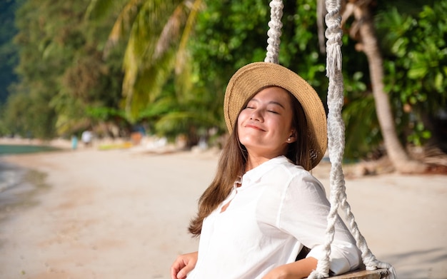 海のそばでスイングと美しい若いアジアの女性の肖像画の画像