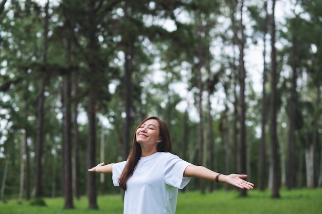 Portrait image of a happy young asian woman with arms opening in the park