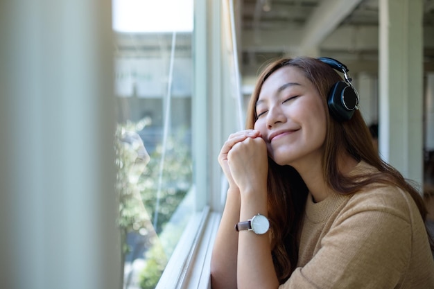 Изображение портрета красивой молодой азиатской женщины любит слушать музыку с наушниками