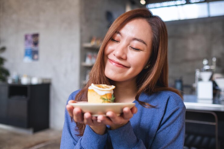 Photo レモンパウンドケーキを握って食べている若いアジア人の女性の肖像画