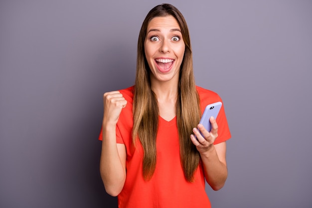 Portrait of impressed brunette lady in red t-shirt posing against the purple wall