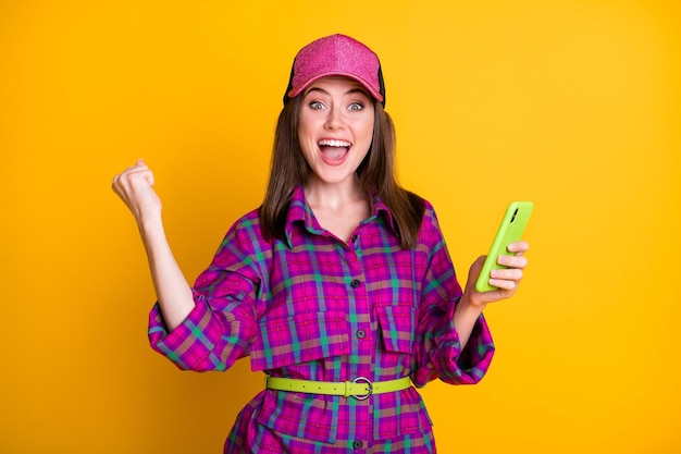 Portrait of impressed lady arm fist up open mouth yeah success purple plaid wear isolated on yellow color background