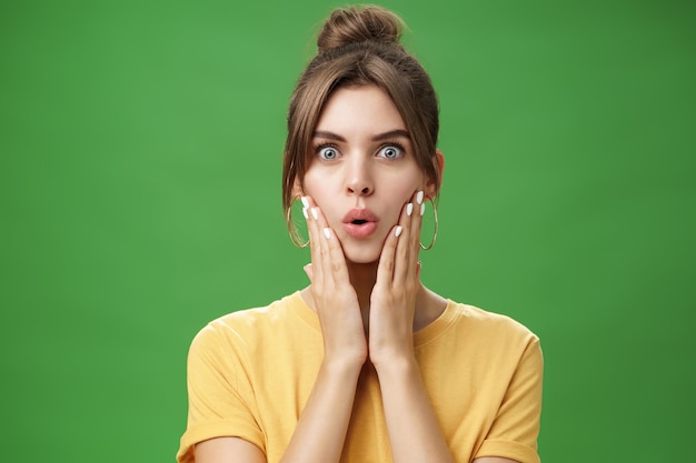 Portrait of impressed and shocked cute feminine woman in yellow t-shirt