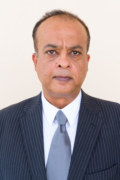 Portrait of Indian businessman against plain wall outdoors looking at camera