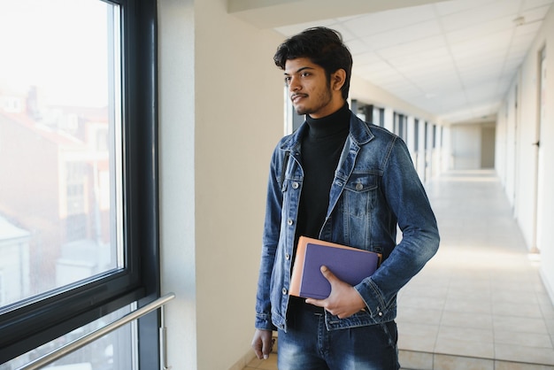 Portrait of indian college boy holding books.