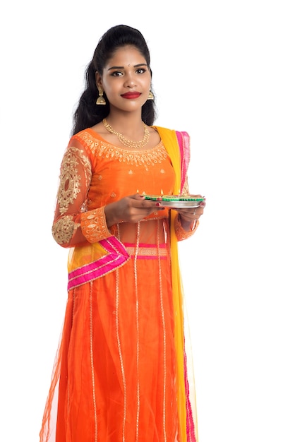 Portrait of an Indian Girl holding Diya Celebrating Diwali or Deepavali with oil lamp during the festival of light on white