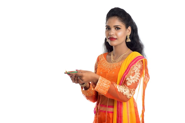 Portrait of an Indian Girl holding Diya Celebrating Diwali or Deepavali with oil lamp during the festival of light on white