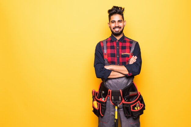 Portrait of indian happy handyman with tool belt isolated on yellow space