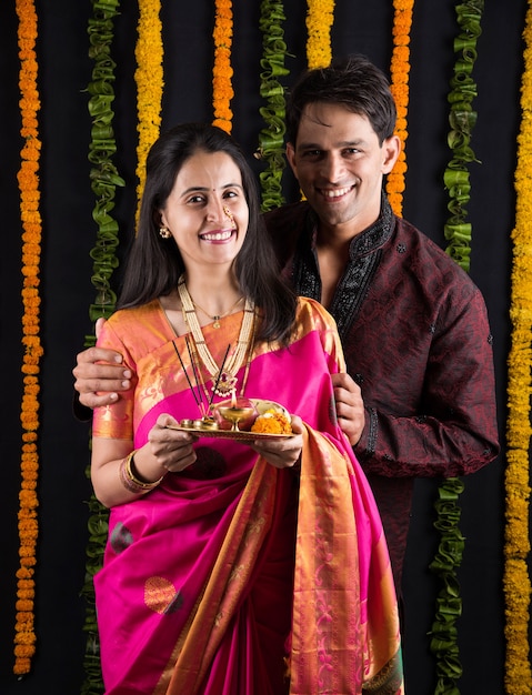 Photo portrait of indian married couple in traditional wear in namaskara or prayer or welcoming pose or holding puja thali