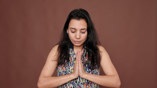 Portrait of indian peaceful woman doing zen meditation on\
camera, concentrating for harmony and mindfulness. doing yoga pose\
for meditation, wellness and life peace to advertise\
recreation.