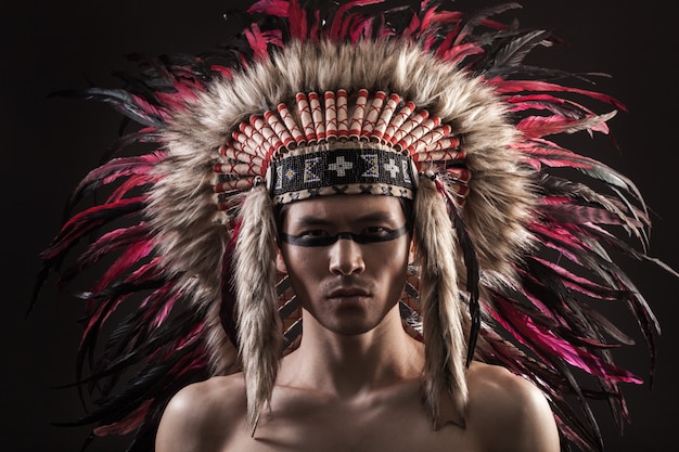 Portrait of the indian strong man posing with traditional native american make up 