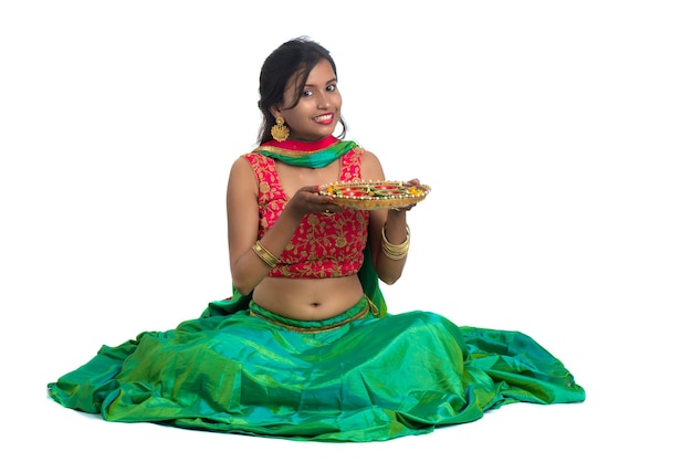 Photo portrait of an indian traditional girl celebrating diwali or deepavali holding oil lamp during the festival of light on white