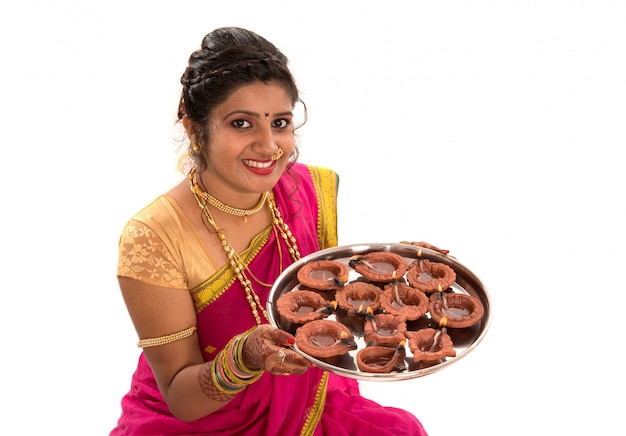 Portrait of a Indian Traditional Girl holding diya, Diwali or deepavali photo with female hands holding oil lamp during festival of light on white surface