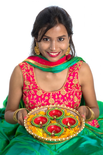 Portrait of a Indian Traditional Girl holding Diya, Girl Celebrating Diwali or Deepavali with holding oil lamp during festival of light on white background