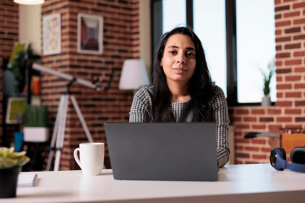 Ritratto di donna indiana che lavora in remoto da casa sul laptop alla scrivania, naviga in internet e invia e-mail con report di scartoffie. utilizzo del computer per studiare online durante il webinar di classe, lavoro da freelance.