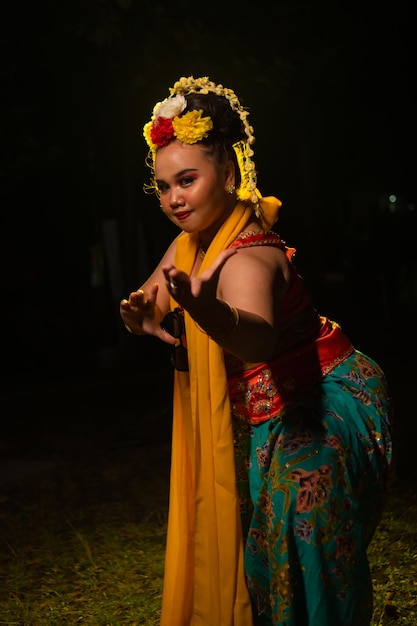 Photo portrait of an indonesian dancer with a gold belt dancing gracefully at night