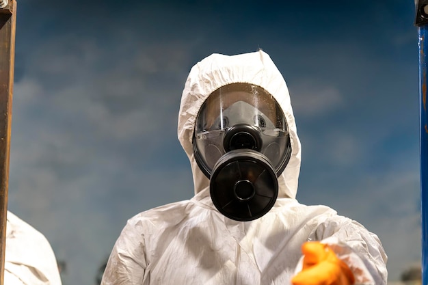 Portrait industrial worker technologist wearing hazmat suit in
production plant man in white protective uniform with protective
mask handling hazardous chemicals