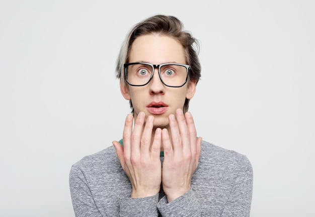 Portrait of insecure and scared handsome young man wear glasses hold hands pressed to chest