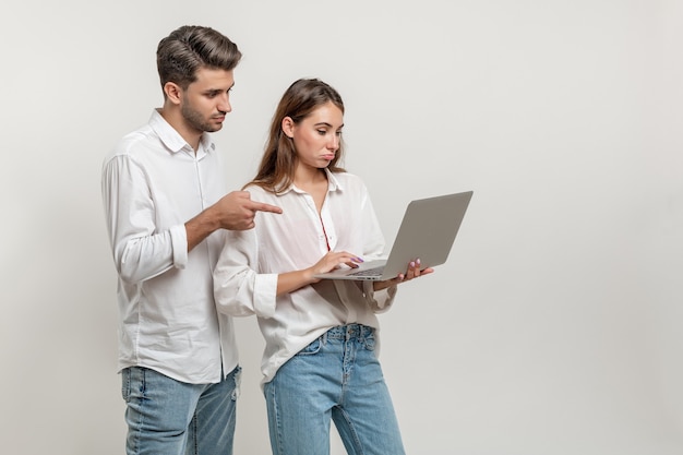 Portrait of inspired couple using laptop browsing sites social networks pointing on the screen