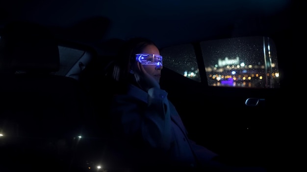 Photo portrait of an intelligent young woman sitting in the back of a car wearing virtual reality glasses