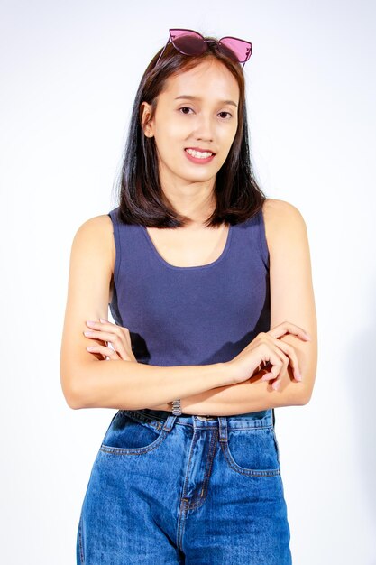 Portrait isolated closeup studio cutout shot of Asian female model in crop top shirt jeans and sunglasses smiling look at camera on white background
