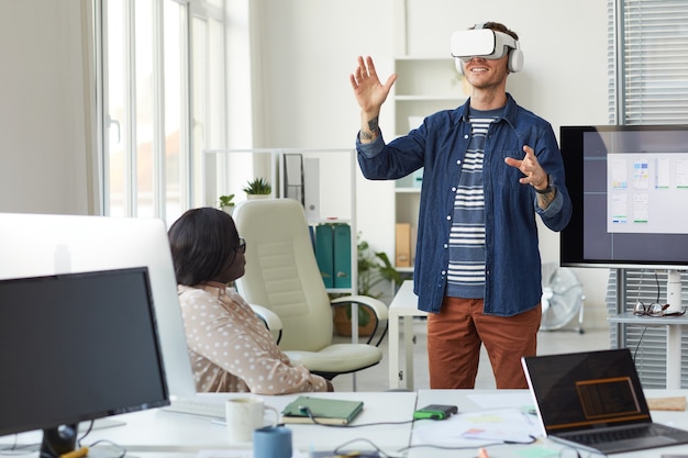 Portrait of IT development team designing immersive reality software with focus on man wearing VR headset in office, copy space